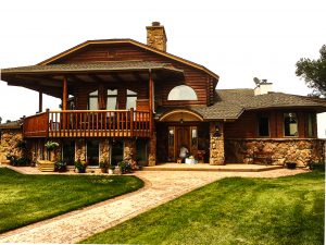 Log sided home with stone on lower. Green grass.